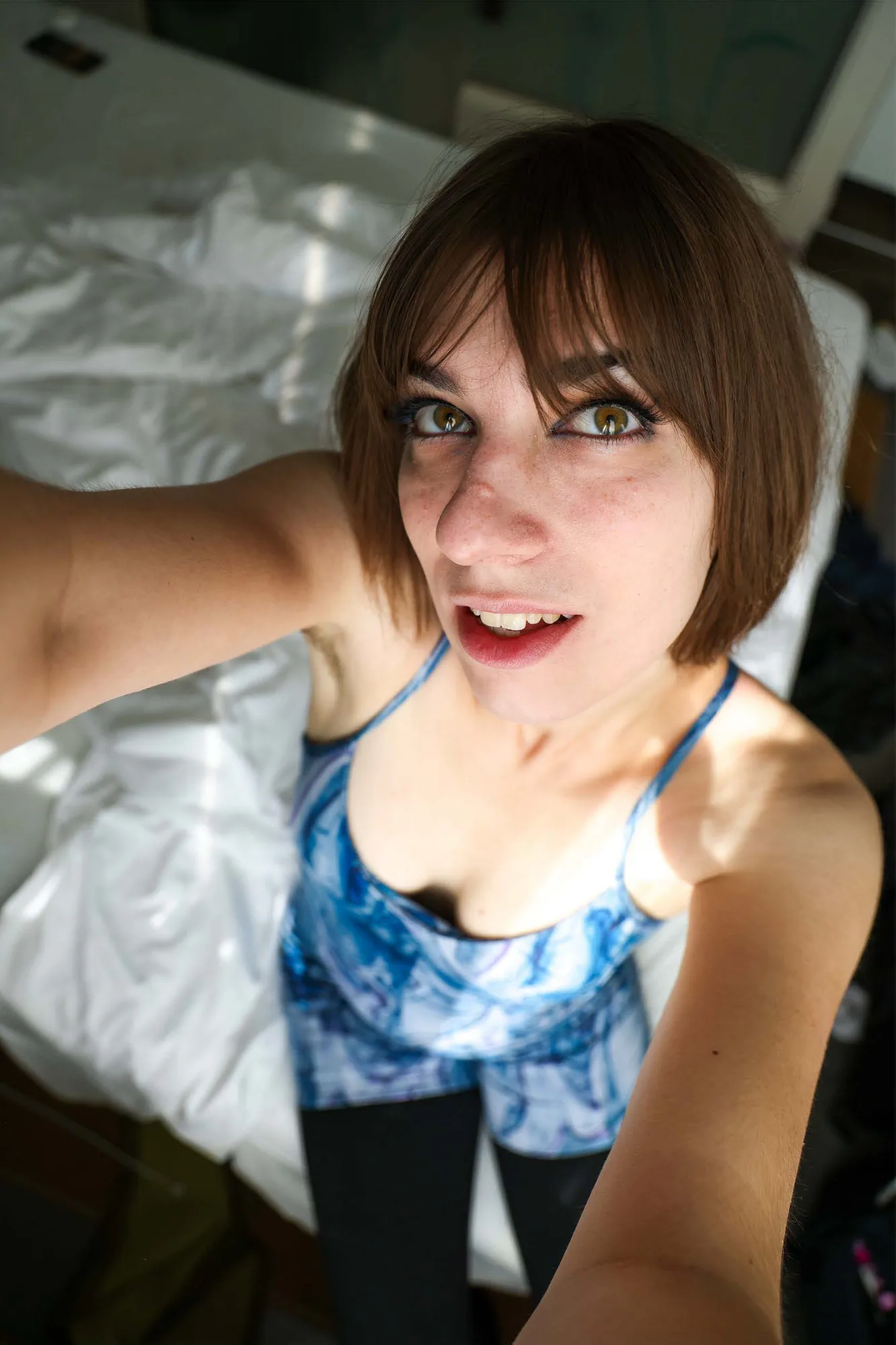 Kady, a selfie from above, sitting on white sheets in a blue marbled top.